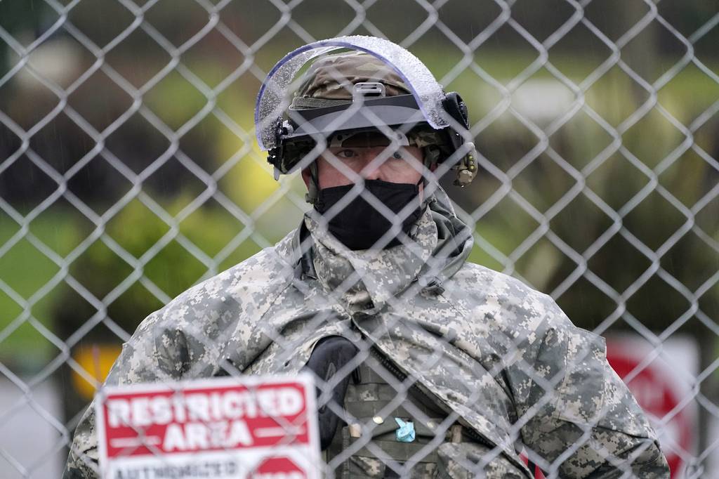 A member of the Washington National Guard stands at a fence surrounding the Capitol in anticipation of protests Monday, Jan. 11, 2021, in Olympia, Wash.