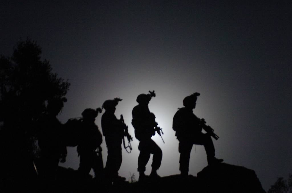 Soldiers from B Company, 1st Battalion, 32nd Infantry Regiment, 10th Mountain Division, await orders to move out on a nighttime patrol designed to interrupt movement of enemy fighters in the Nuristan province of Afghanistan, Sept. 1, 2006.