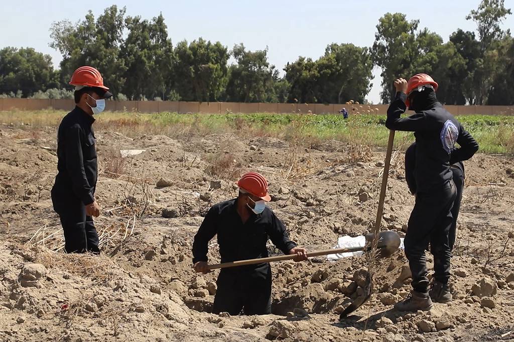 This July 14, 2019, frame grab from video, shows Syrian workers of the Civil Council of Raqqa digging for human remains at the site of a mass grave believed to contain the bodies of civilians and Islamic State militants, in Raqqa.