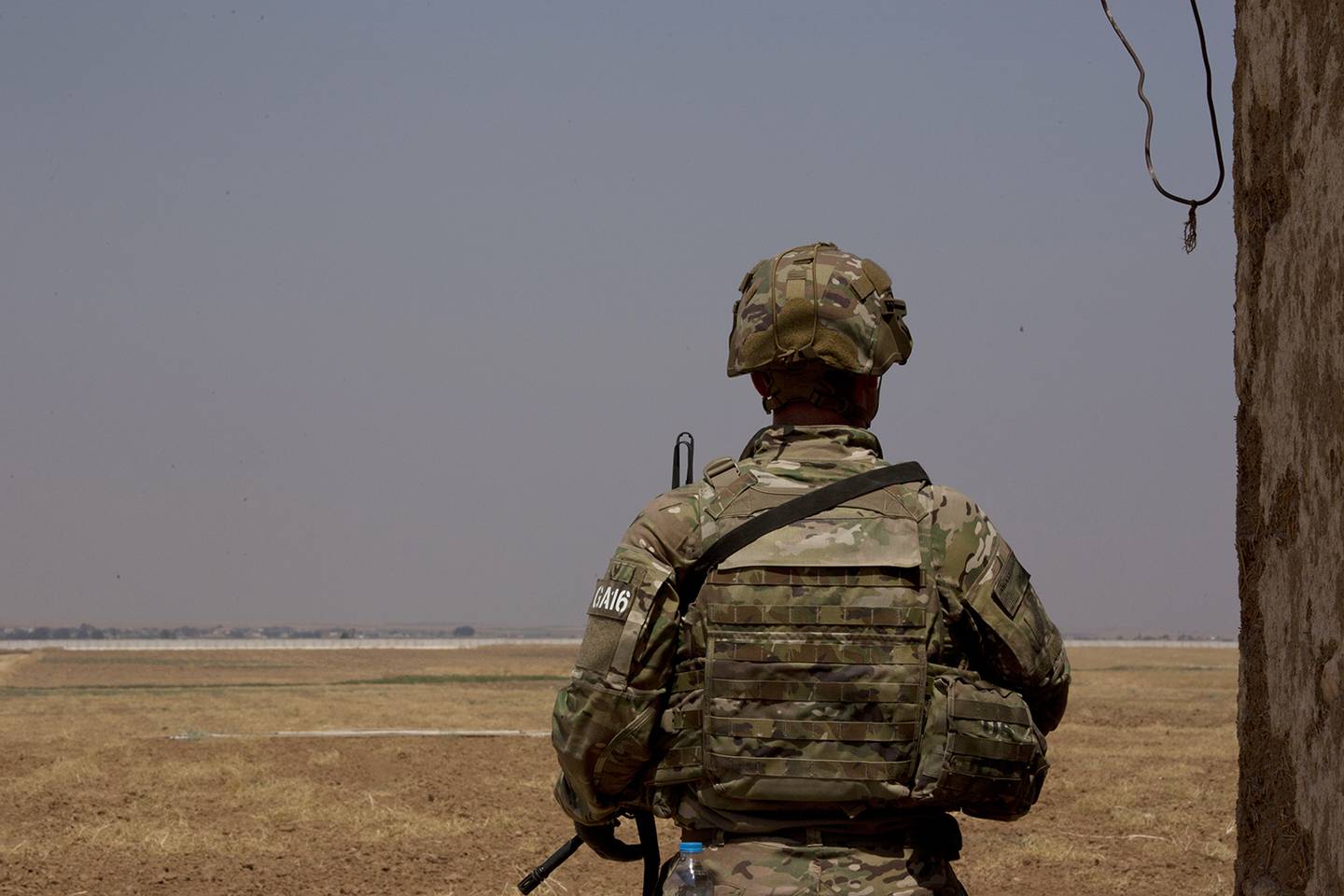 A U.S. soldier stands guard, facing the Turkish border in the safe zone near Tal Abyad, Syria, during a joint patrol Friday, Sept. 6, 2019.