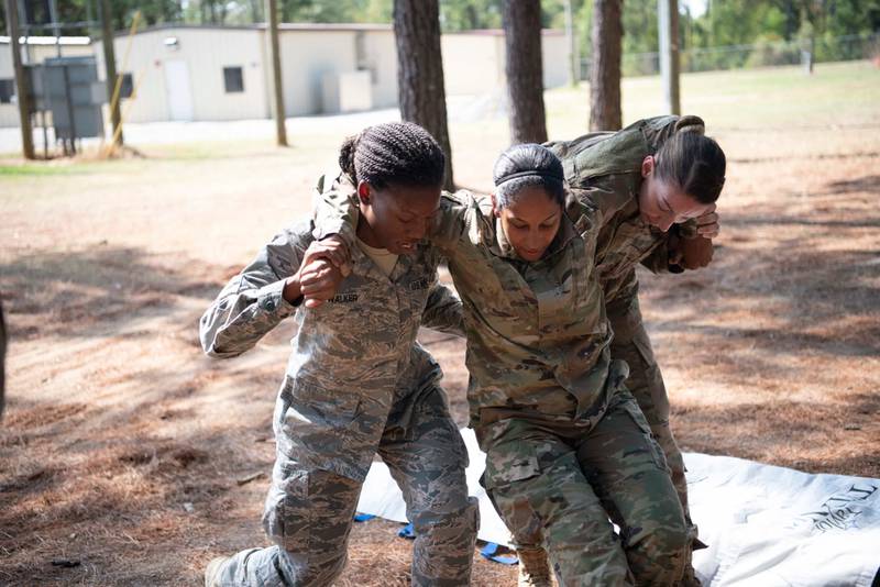Officer trainees, as part of the Air Force's Officer Training School, evacuate a wounded airmen during a mock combat scenario, Sept. 19, 2019, at Maxwell Air Force Base, Alabama. Pregnant people may now apply for a spot at OTS under a recent change in Air Force policy. (Senior Airman Francisco Melendez-Espinosa/Air Force)