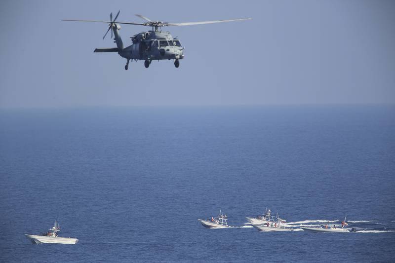 In this Dec. 21, 2018, file photo, a U.S. MH-60 Seahawk helicopter flies over Iranian Revolutionary Guard patrol boats in the Strait of Hormuz.