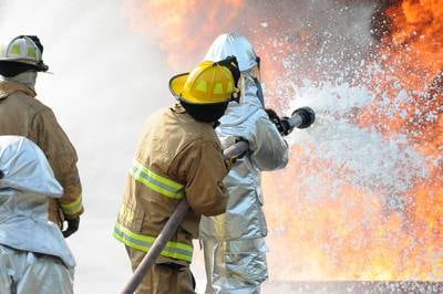U.S. Air Force and New Jersey state fire protection specialists from the New Jersey Air National Guard's 177th Fighter Wing battle a simulated aircraft fire with Aqueous Film Forming Foam at Military Sealift Command Training Center East in Freehold, N.J., on June 12, 2015.
