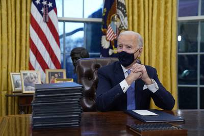 President Joe Biden waits to sign his first executive order in the Oval Office of the White House on Wednesday, Jan. 20, 2021, in Washington.