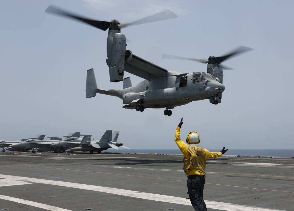 In this image provided by the U.S. Navy, Aviation Boatswain's Mate 2nd Class Nicholas Hawkins, signals an MV-22 Osprey to land on the flight deck of the USS Abraham Lincoln in the Arabian Sea on May 17, 2019.