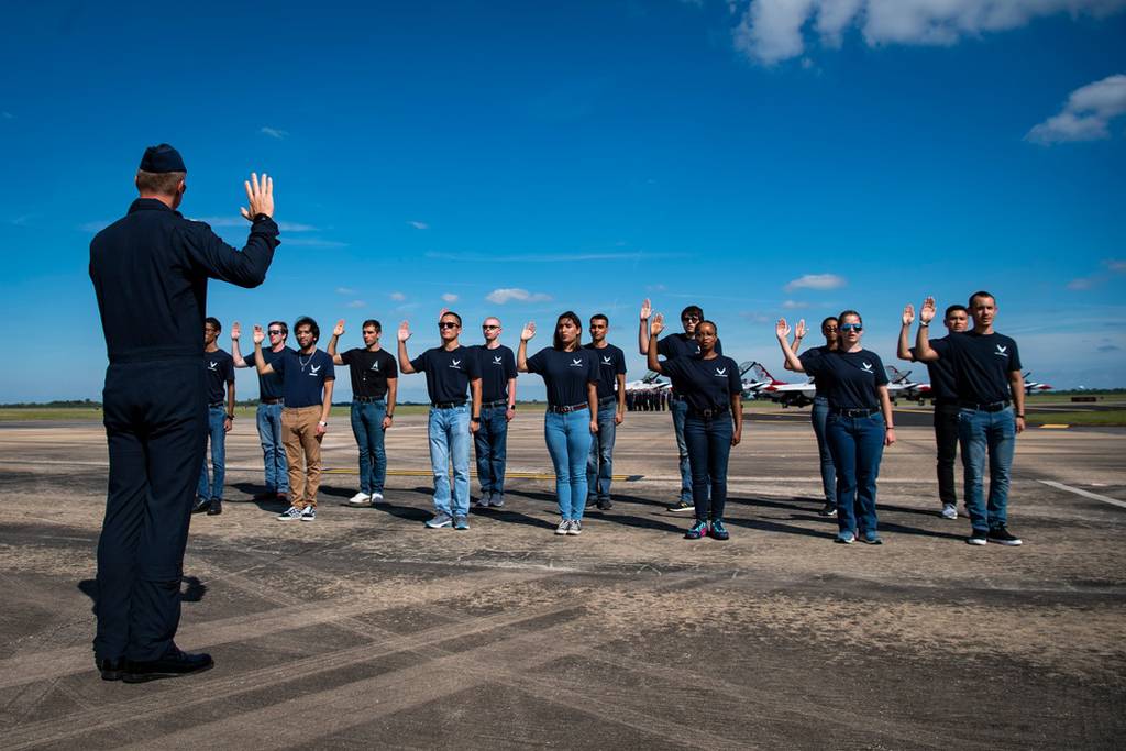 Lt. Col. Noel Colls, flight surgeon for the Air Force's "Thunderbirds" air demonstration squadron, administers the oath of enlistment to new recruits during the Wings Over Houston Airshow in Houston, Texas, Oct. 9, 2021. The team typically performs an enlistment ceremony at each show site. (Staff Sgt. Andrew D. Sarver/Air Force)