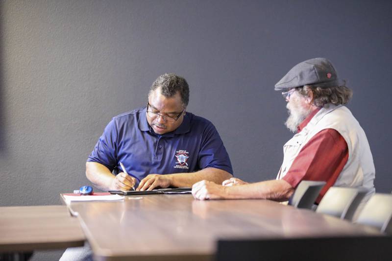 Forrest Powell, left, deputy director, state of Alaska Office of Veterans Affairs, assists local veterans with their earned benefits during an outreach event at the Aurora Inn in Nome, Alaska, July 9, 2022.