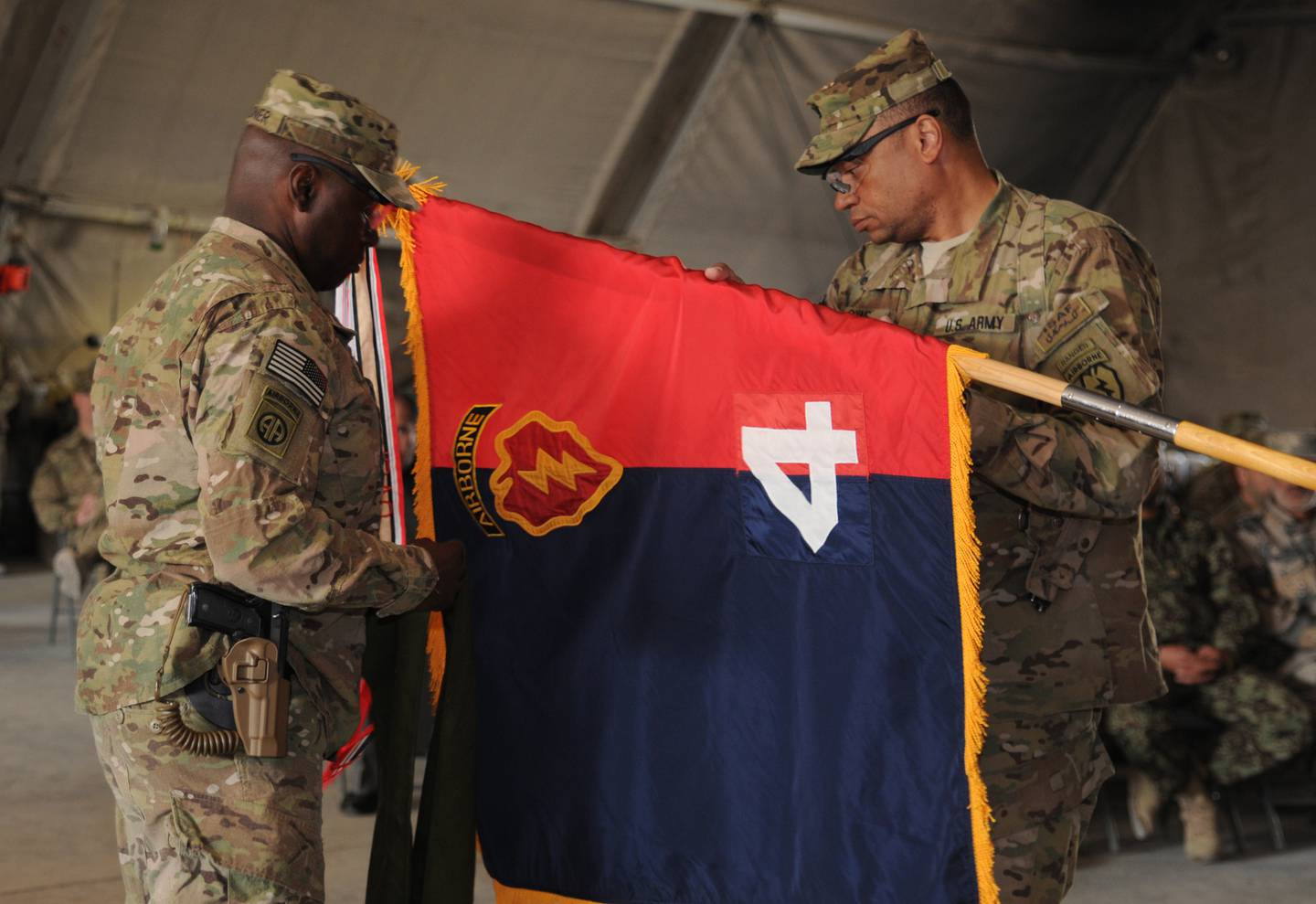 Army Col. Morris Goins, 4th Brigade Combat Team (Airborne), 25th Infantry Division, Task Force Spartan commander, and Army Command Sgt. Maj. Terry Gardner, command sergeant major of the 4th Brigade Combat Team (Airborne), 25th Infantry Division, Task Force Spartan, uncase their “colors” as the brigade assumes responsibility from TF Duke.