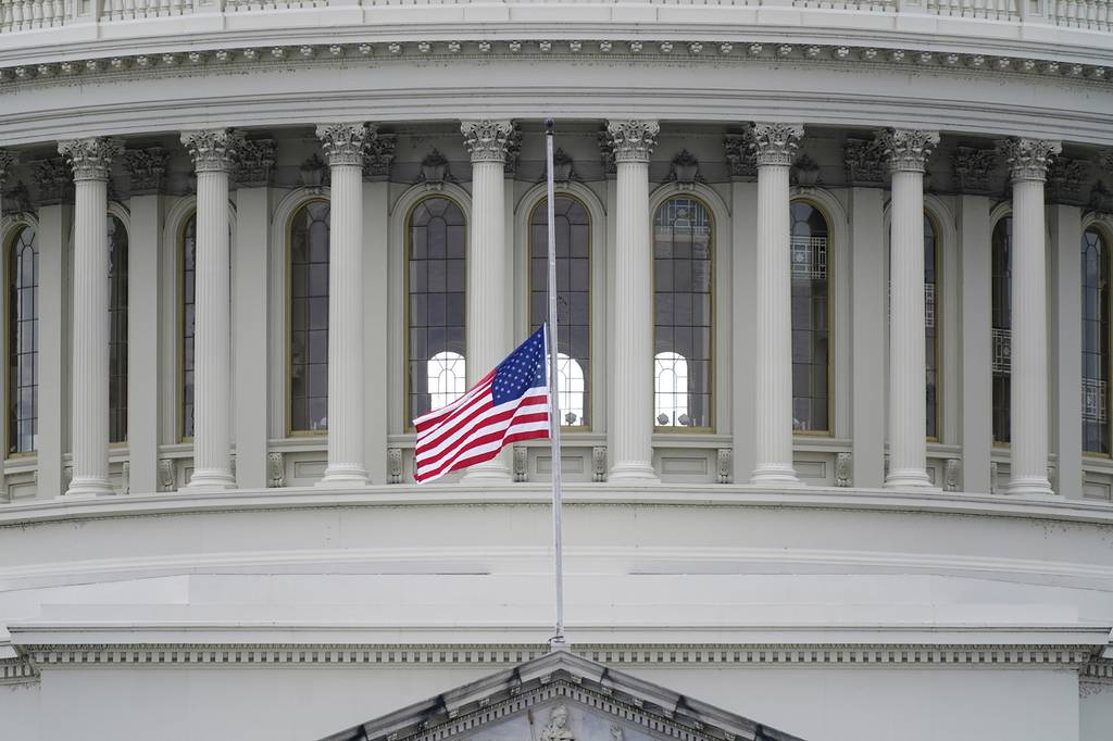 An American flag flies at half-staff in remembrance of U.S. Capitol Police Officer Brian Sicknick above the Capitol Building in Washington, Friday, Jan. 8, 2021.