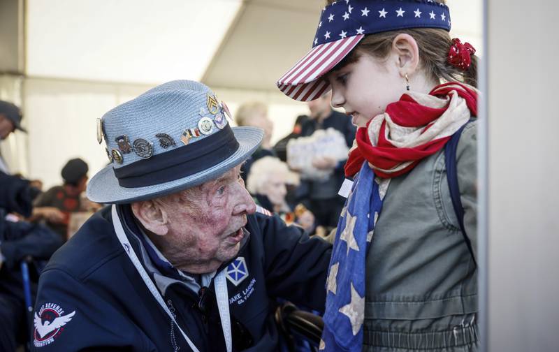 U.S. veteran Jake M. Larson talks to a girl who wears an American flag around her neck during a gathering in preparation of the 79th D-Day anniversary in La Fiere, Normandy, France, Sunday, June 4, 2023.