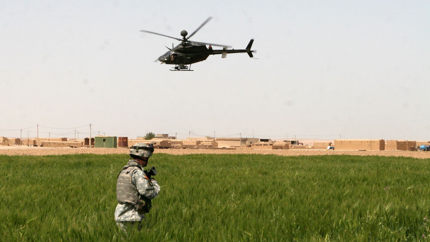 A soldier from Company C, 1st Battalion, 327th Infantry Regiment, pulls security in a town near Kirkuk, Iraq, as a Kiowa Warrior helicopter from 2nd Squadron, 17th Cavalry Regiment, patrols the area surrounding the village in 2006. ( Staff Sgt. Ryan Matson/Army)