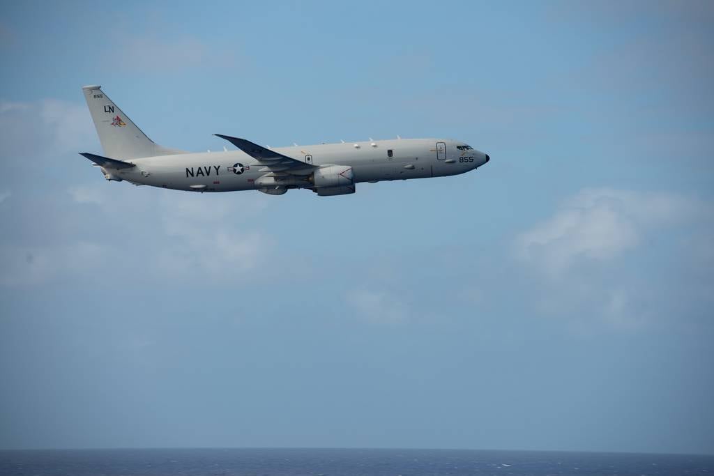A P-8A Poseidon flies by the aircraft carrier Nimitz in the Philippine Sea, Feb. 24, 2023.
