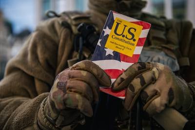 National Guard Master Sgt. George Roachs holds up a pamphlet of the U.S. Constitution on Jan. 17, 2021, in Washington. (