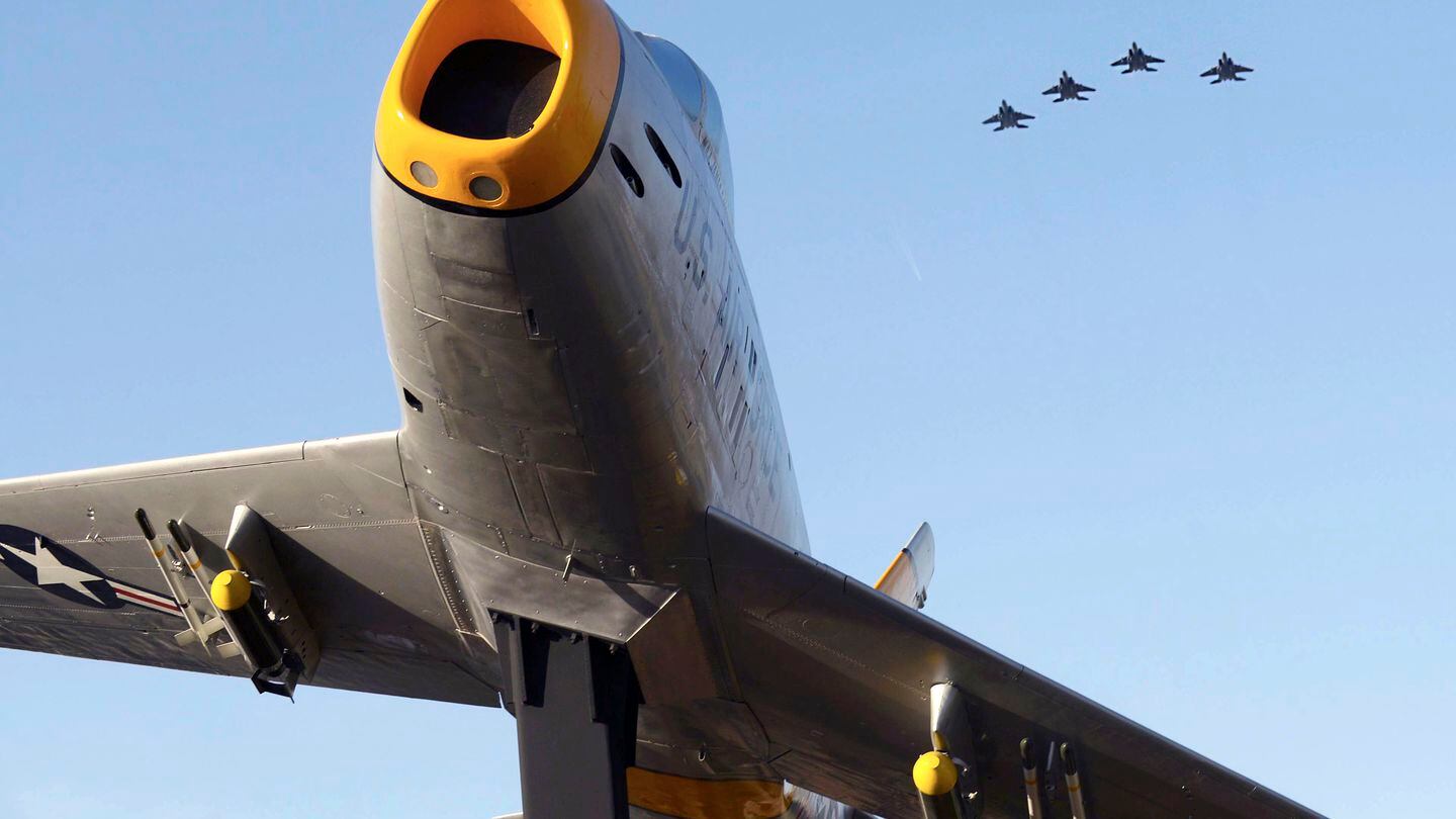 Four F-15E Strike Eagles fly by an F-86 Sabre on display during a 2016 even in Goldsboro, N.C. (Airman 1st Class Ashley Williamson/U.S. Air Force)