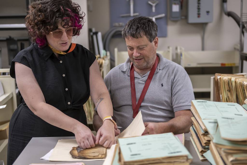 Ashley Cox, a preservation specialist at the National Archives and Records Administration, and NARA Preservation Technician Tom Schmidt assess a record's condition at the National Personnel Records Center in Spanish Lake, Mo., near St. Louis, on June 2, 2023.