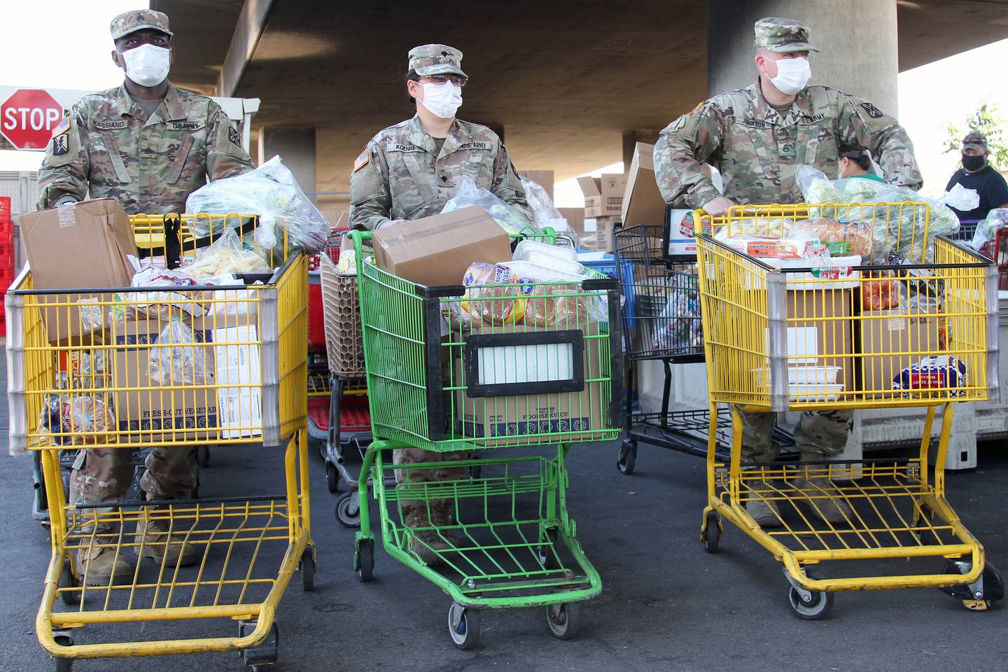 Soldiers with the California National Guard move grocery carts filled with food and await the arrival of recipients on June 26, 2020, at the Stockton/San Joaquin Emergency Food Bank in Stockton, Calif.