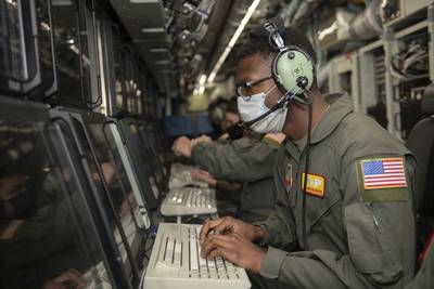 Senior Airman Christian Jackson, a cryptologic language analyst with the 97th Intelligence Squadron, sits at a computer simulating his in-flight duties at Lincoln Airport, Neb., May 11, 2021. Airmen from different Offutt Air Force Base, Neb., squadrons posed for photos on a RC-135V/W Rivet Joint. (Staff Sgt. Jessica Montano/Air Force)