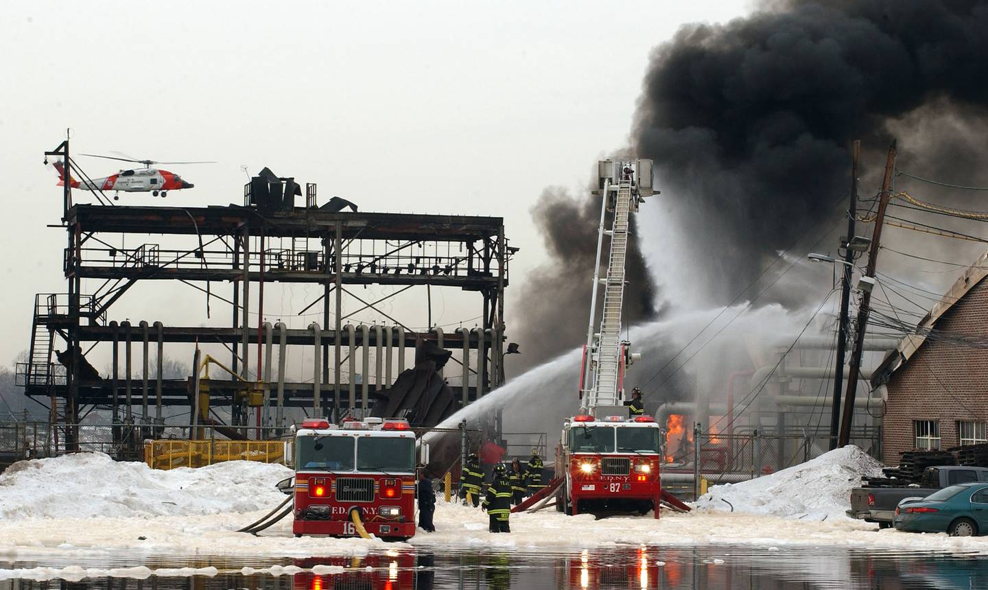 A U.S. Coast Guard rescue helicopter flies over Bouchard Barge 125 shortly after it exploded at the ExxonMobil petroleum storage facility February 21, 2003 in the Staten Island borough of New York City.