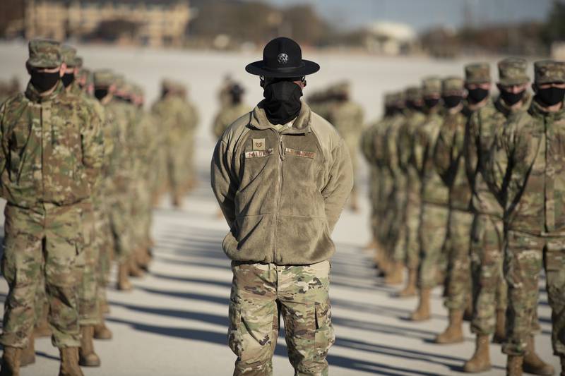 A military training instructor, center, stands in front of his flight during a basic military graduation and coining ceremony Dec. 10, 2020, at Joint Base San Antonio-Lackland, Texas.