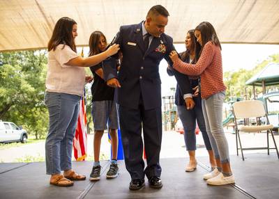 Chief Master Sgt. Juan Rodriguez, 149th Fighter Wing Medical Group Detachment 1 chief enlisted leader, has his new rank put on by his family during his promotion ceremony, August 15, 2021, at Joint Base San Antonio-Lackland, Texas. (Staff Sgt. Derek Davis/Air National Guard)