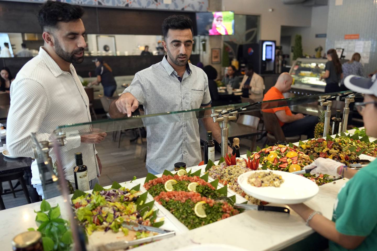 Abdul Wasi Safi, right, and his brother Samiullah pick out food for lunch, Wednesday, April 26, 2023, in Houston.
