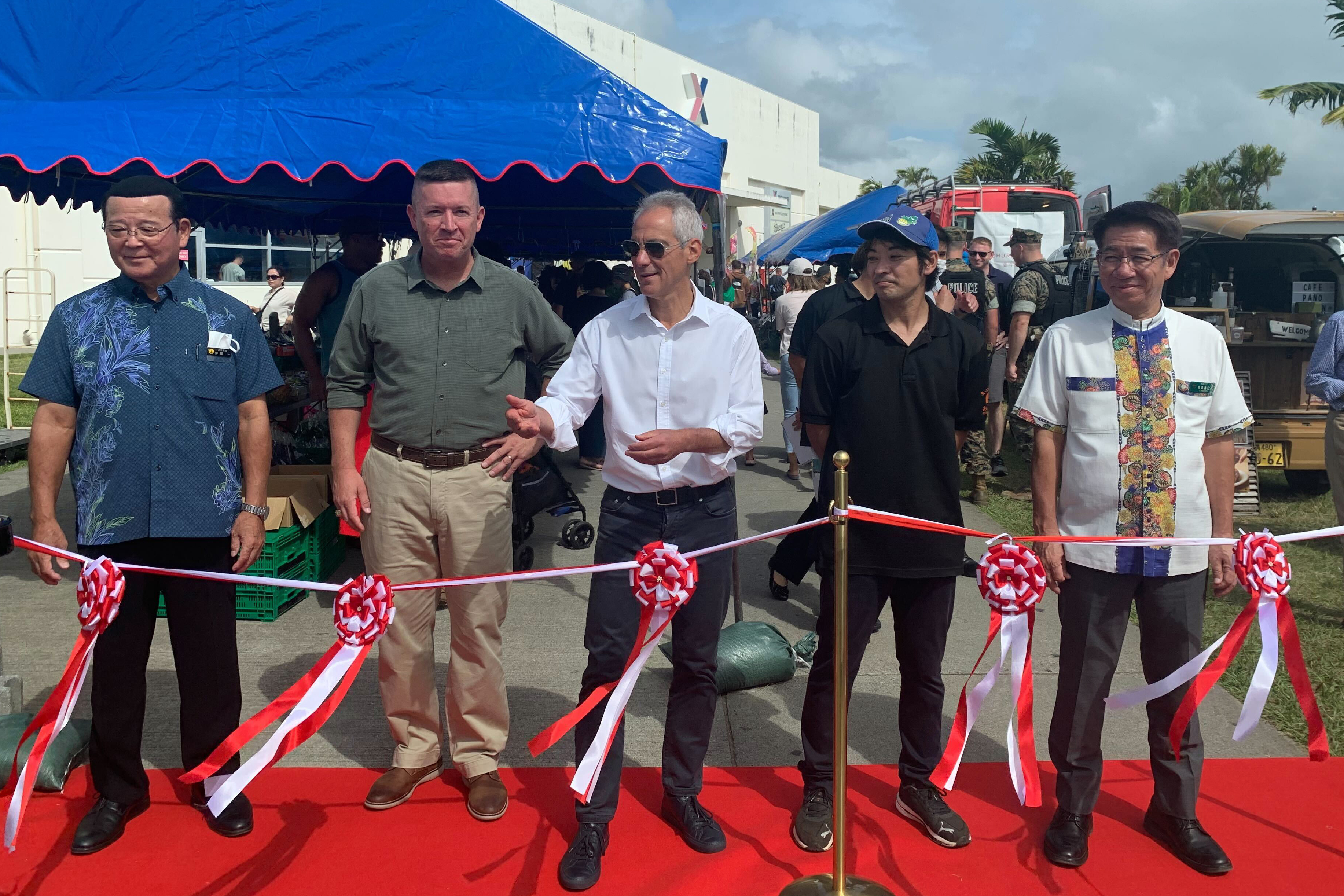 Okinawa's Kin town Mayor Hajime Nakama, from left, III Marine Expeditionary Force Commander Lt. Gen. James Bierman, U.S. Ambassador to Japan Rahm Emanuel, an unidentified local produce vendor from Onna village and Onna village Mayor Yoshimi Nagahama prepare to cut the ribbon on the farmers market at Camp Hansen, a U.S. Marine Corps base on a southern Japanese island of Okinawa, Sunday, Oct. 30, 2022.